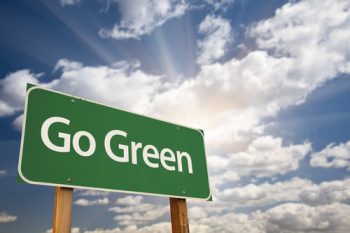 Go Green Road Sign Against Dramatic Clouds, Sky and Sun Rays